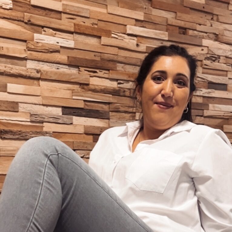Nadine Lauer, Coach für selbstbestimmtes Leben, sitzt entspannt und lächelt in die Kamera.
